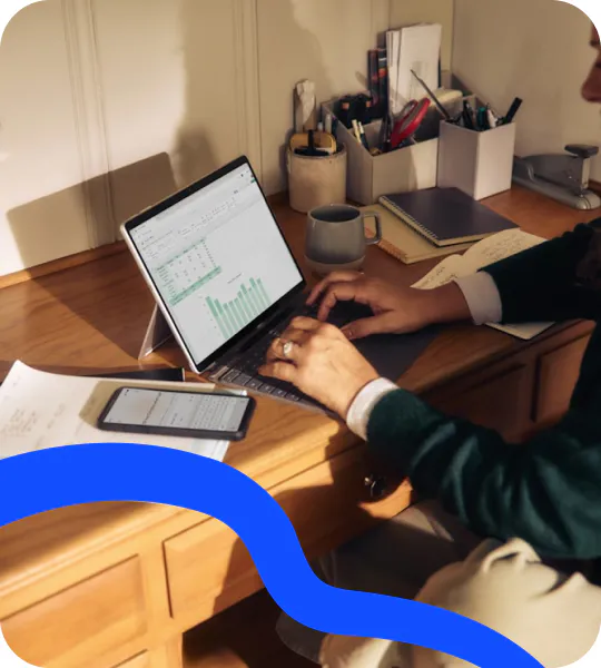 Someone reviewing a spreadsheet of results on a laptop at a wooden desk
